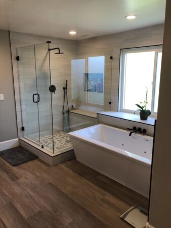 New bathroom remodel, glass shower enclosure, hardwood floors, freestanding tub with dark bronze fixtures, elegant and modern
